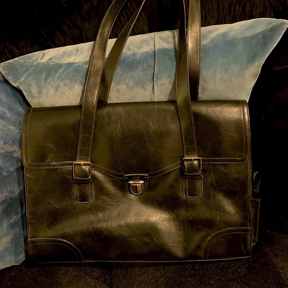 Computer carrying tote for laptop with push button buckle closure and side slot.